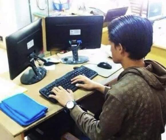 Man typing while looking at the back of two monitors
