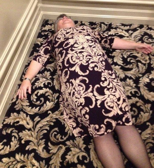 A lady lying on the floor wearing a dress that is the same pattern as the carpet