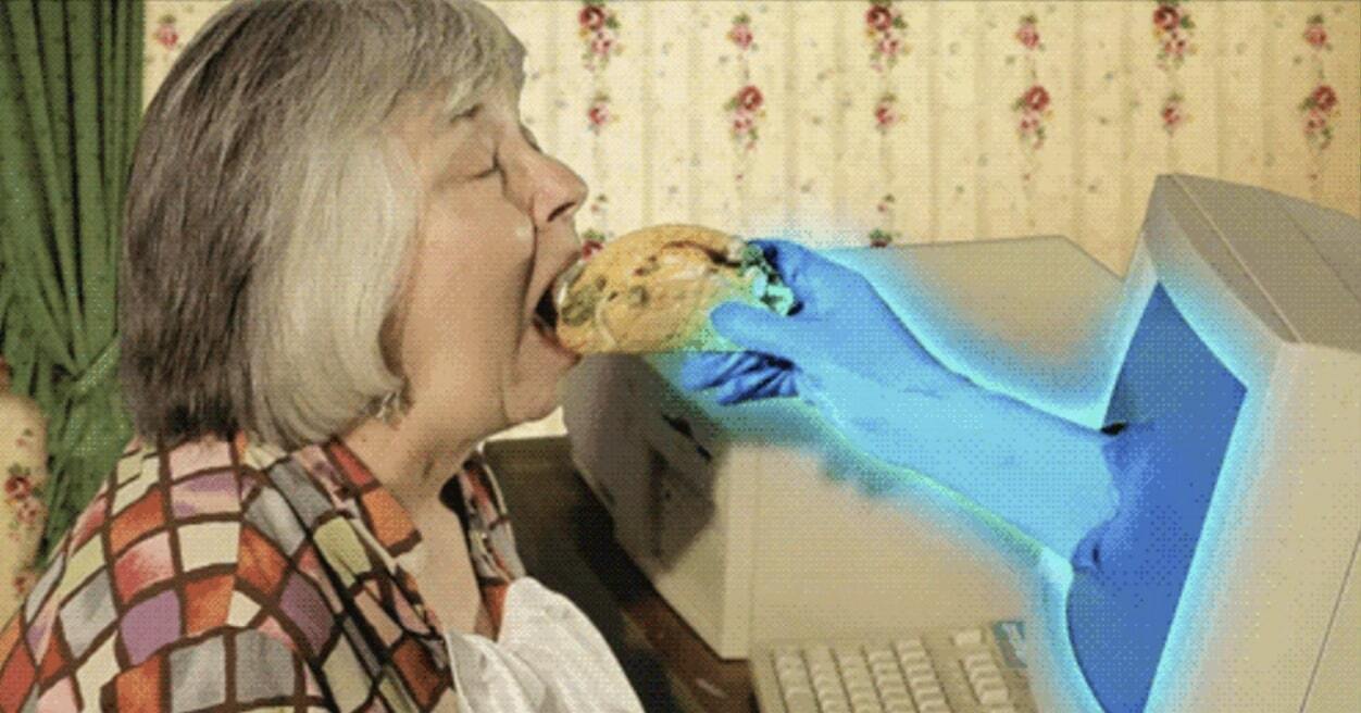 Hand coming from computer feeding a lady some cake