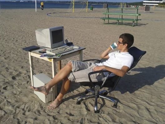 Guy sitting at his computer at the beach