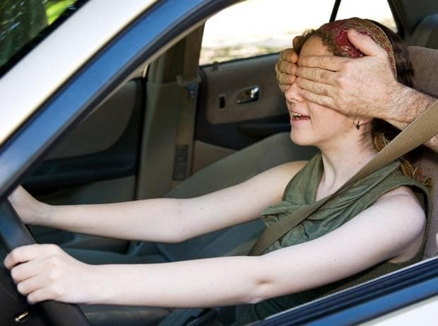Girl driving a car with her eyes covered