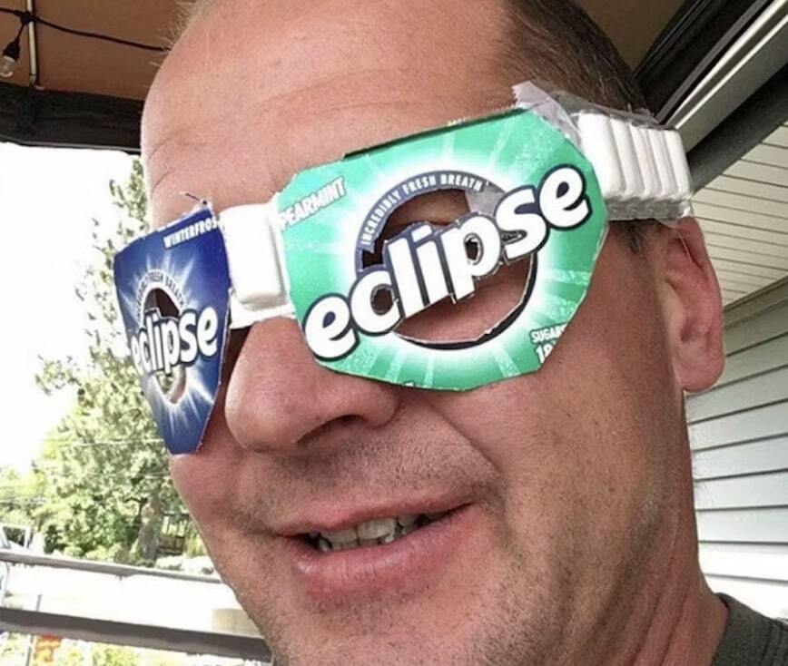 A guy wearing homemade eclipse glasses made out of eclipse gum wrappers