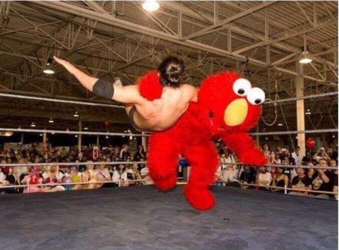 A life-size Elmo tackling a guy in a wrestling ring