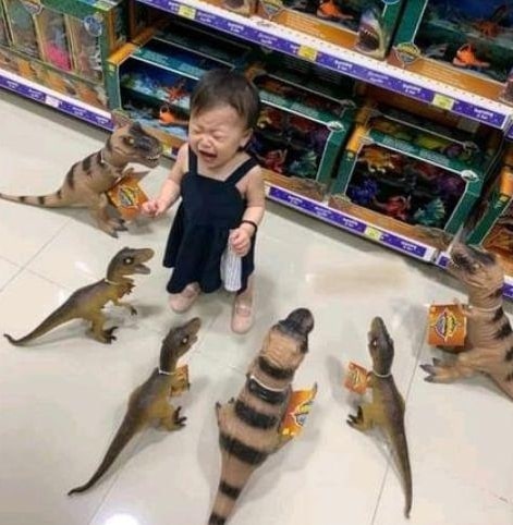 girl crying while surrounded by toy dinosaurs