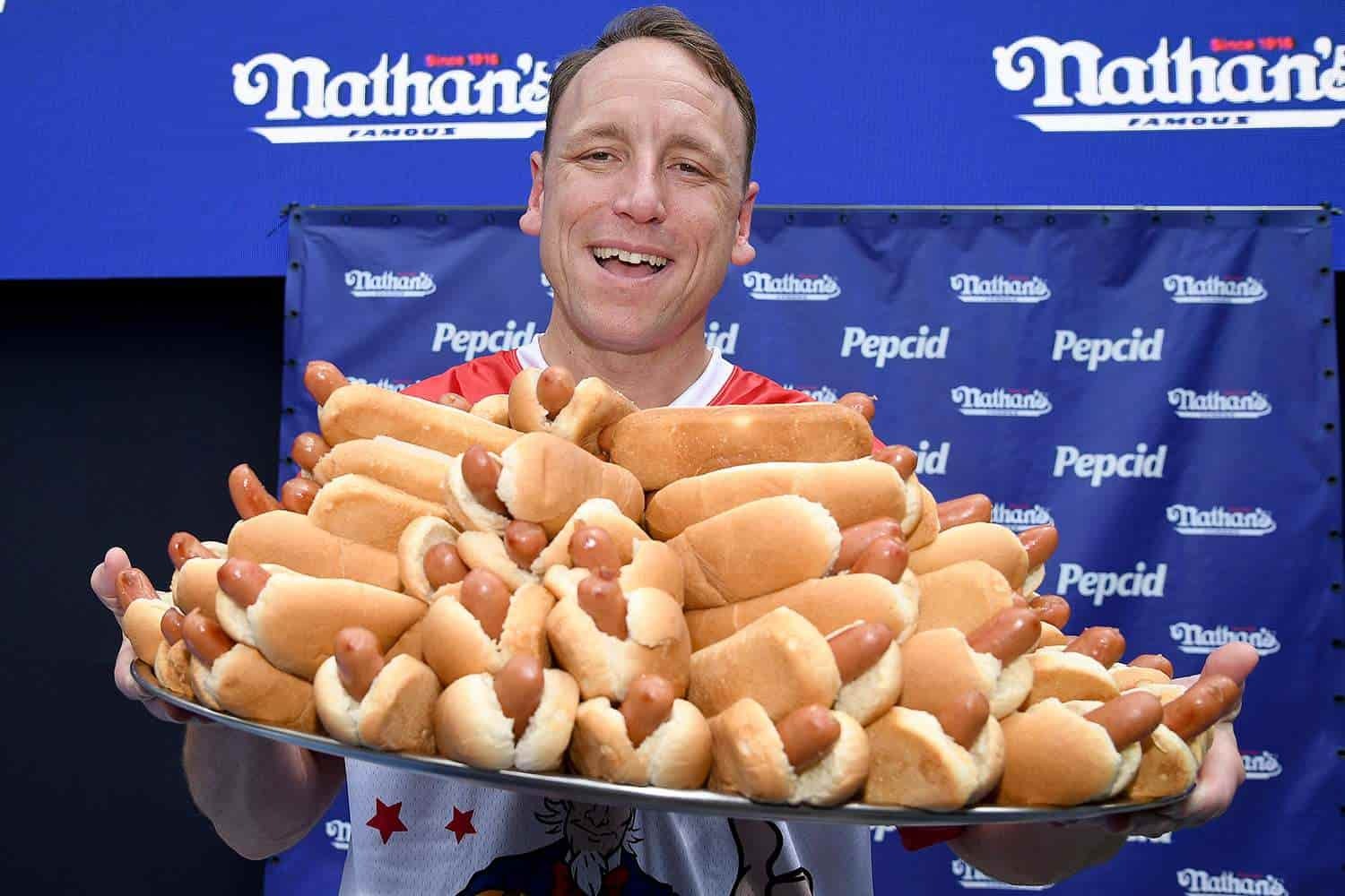 Joey Chestnut standing with a plate full of hotdogs