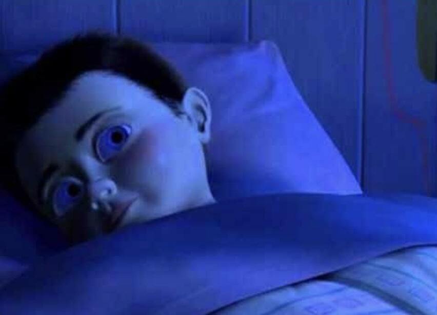 A kid waking up in his bed looking scared