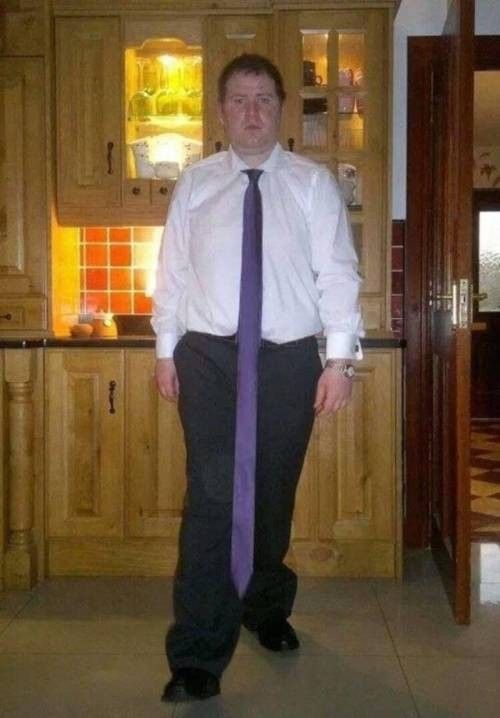 A man wearing an extremely long necktie that trails far below his waist