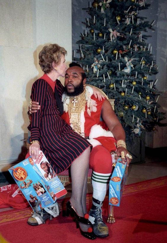 An old lady sitting on Mr T's lap while he's dressed like Santa Claus