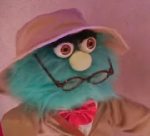 A muppet with his glasses off looking shocked