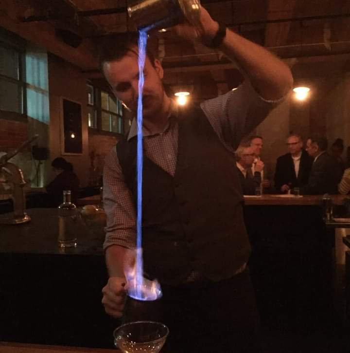 Mixologist pouring a drink that's on fire