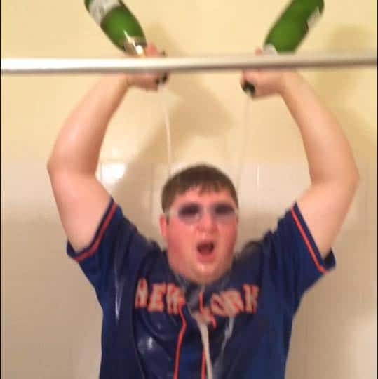 Guy pouring champagne on himself in shower