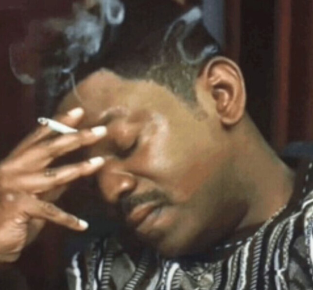 A guy looking tired while smoking a cigarette