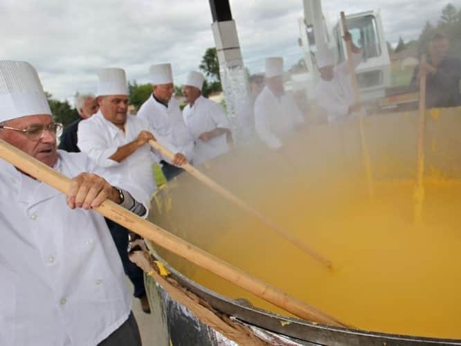 old men stirring a big pot of pasta