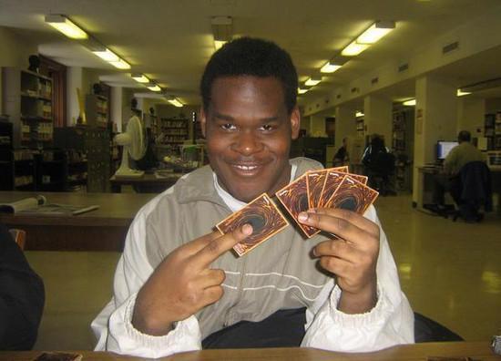 A guy holding Yu-Gi-Oh cards and smiling mischievously