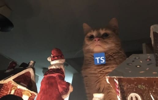 A cat with a typescript logo staring down at christmas decorations