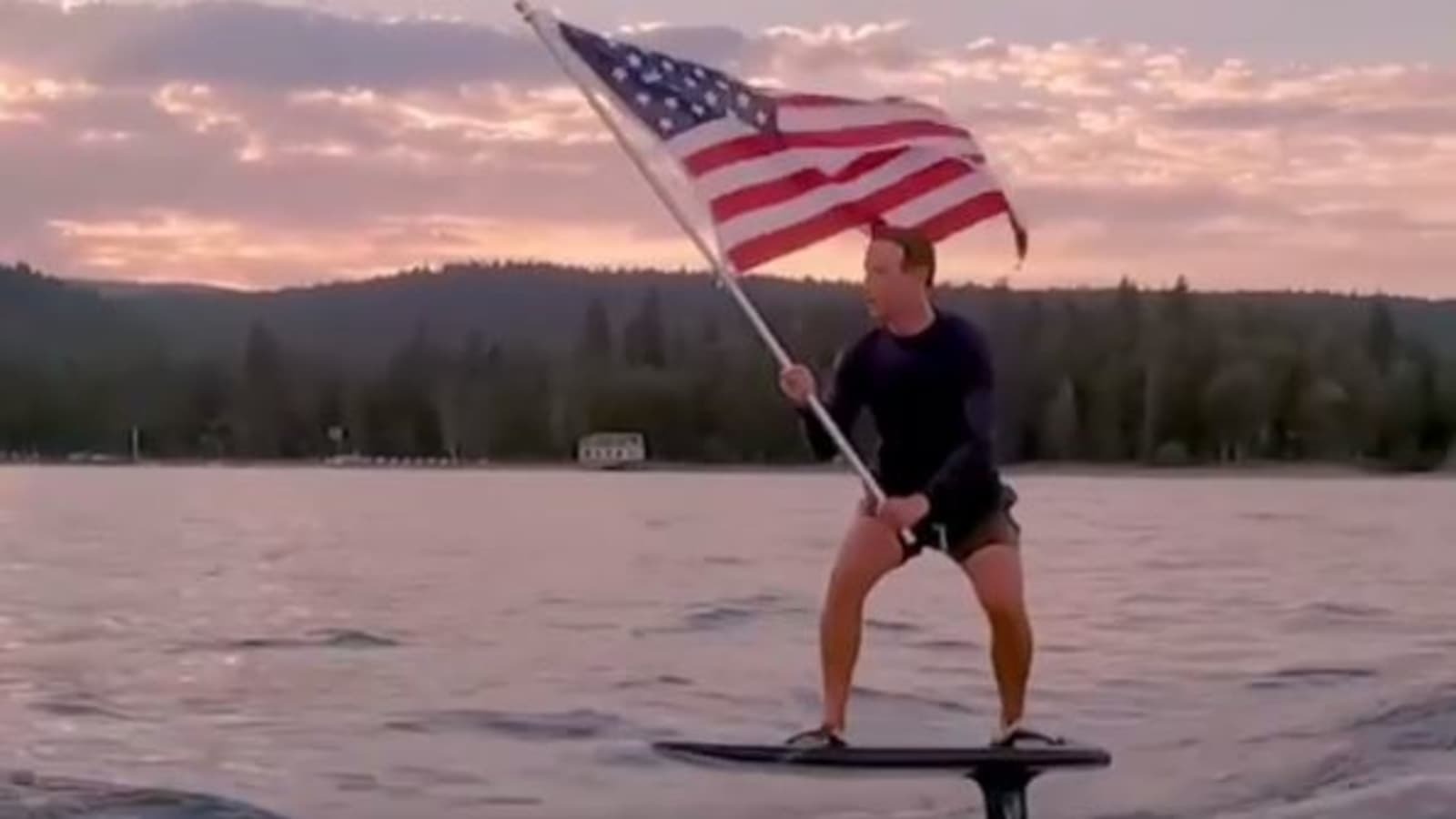 Mark Zuckerberg on his foil surf board waving an American flag